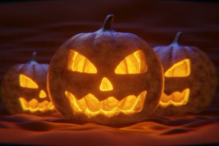Drie verlichte pompoenen halloweenversiering.